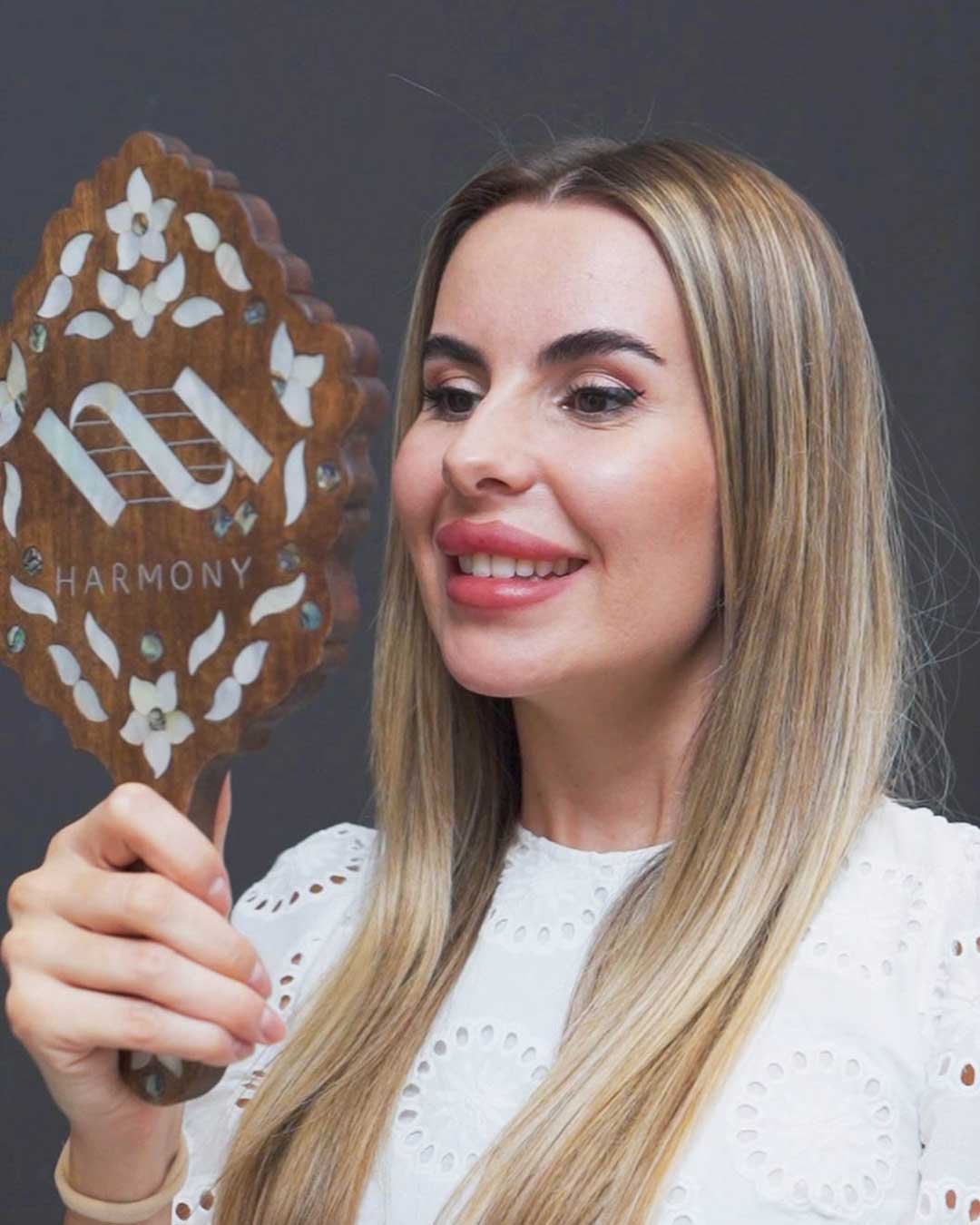 Happy patient admiring her bright smile after in-office teeth whitening at Harmony Medical Center.