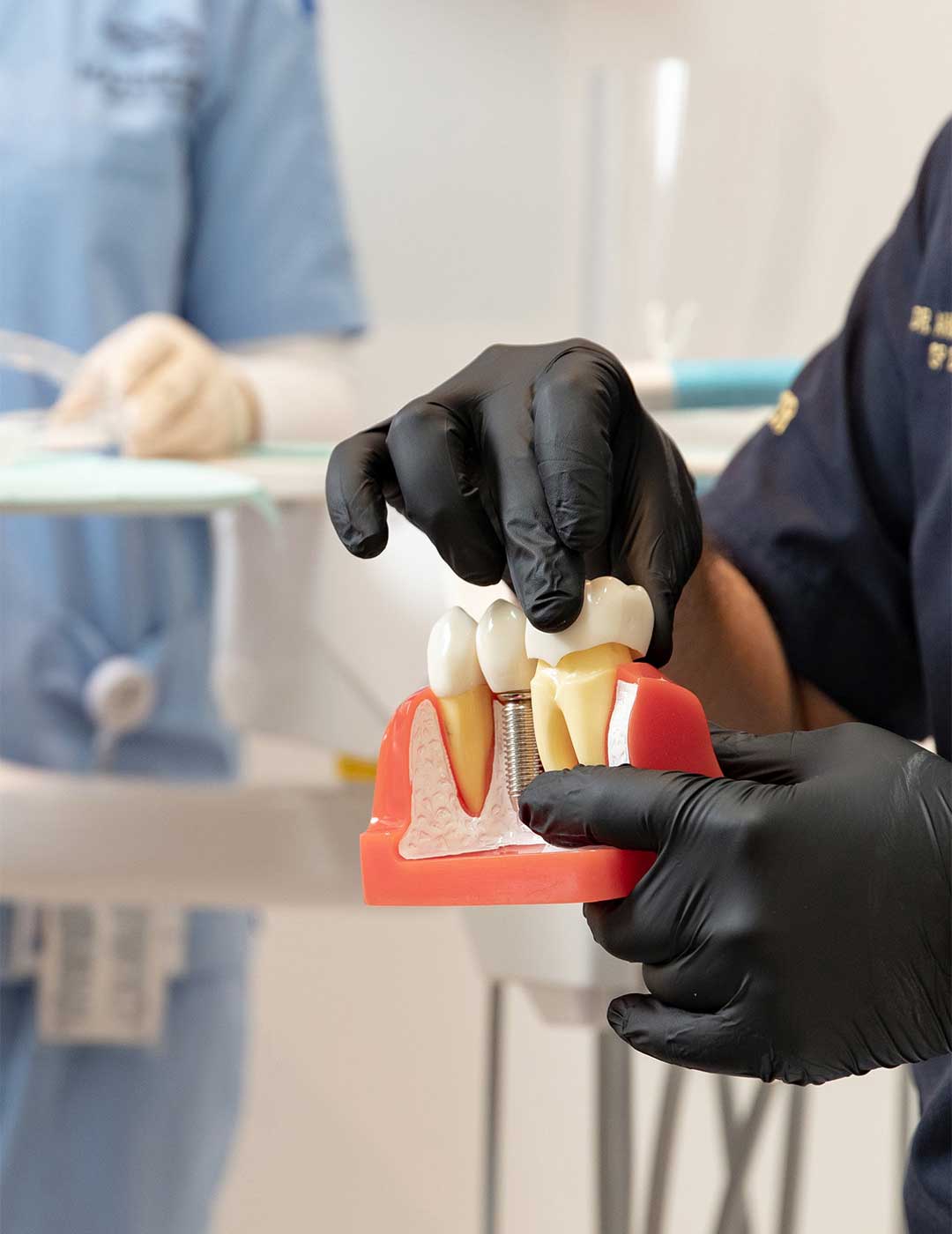 A photo showing an oral surgeon showing a model of dental implants