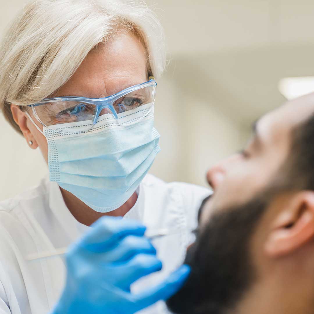 Female specialist periodontist at Harmony Medical Center performing gum disease treatment on a male patient.