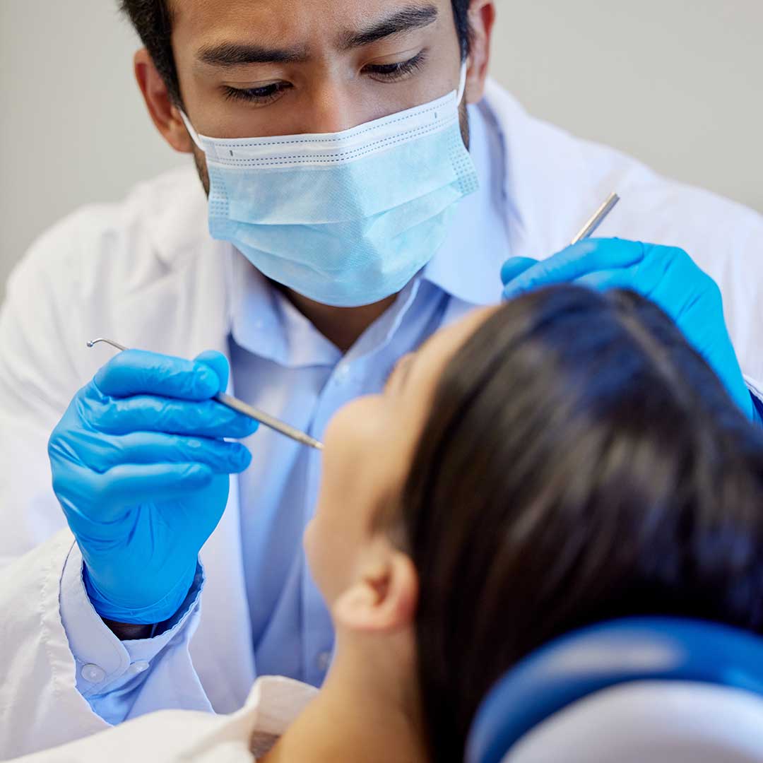Specialist periodontist at Harmony Medical Center examining a female patient for signs of gum disease.