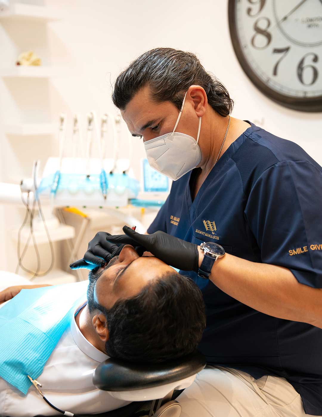 Dr. Ahmad Al Jazairi, Medical Director and Head of Oral & Maxillofacial Surgery at Harmony Medical Center, examining a male patient experiencing TMJ-related jaw pain.